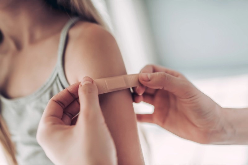 Caregiver gently applying a bandage to a child's arm after care.